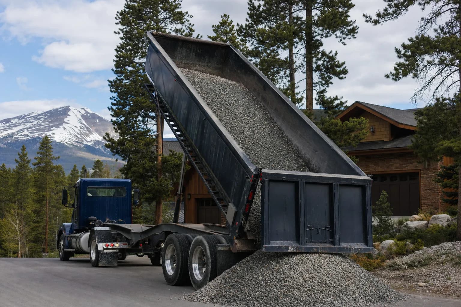 Dump truck delivering gravel to a residential property