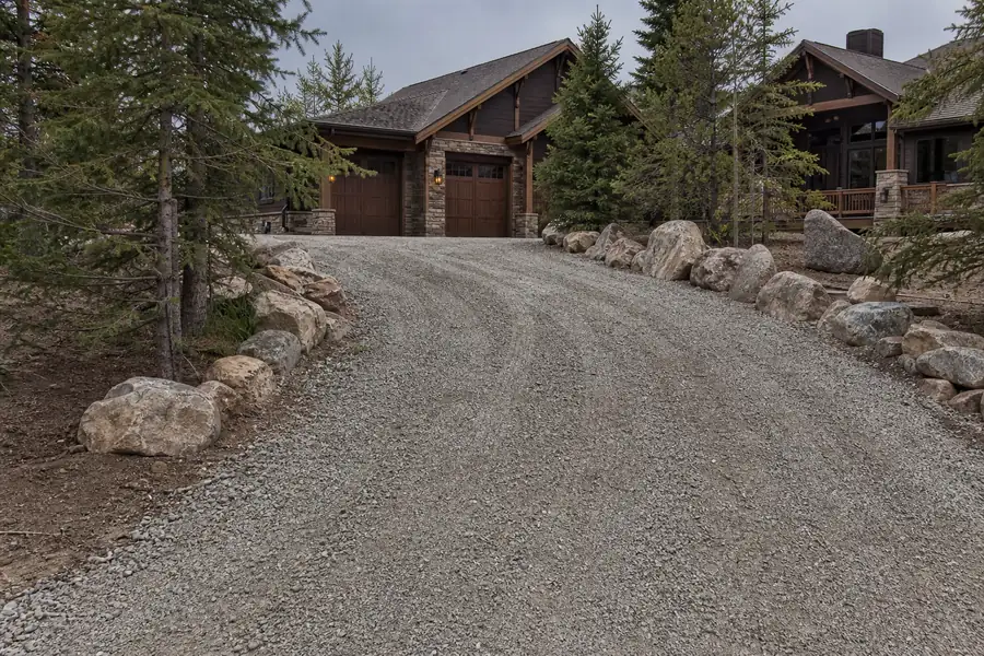 Freshly graded gravel driveway with compacted road base leading up to a Colorado home