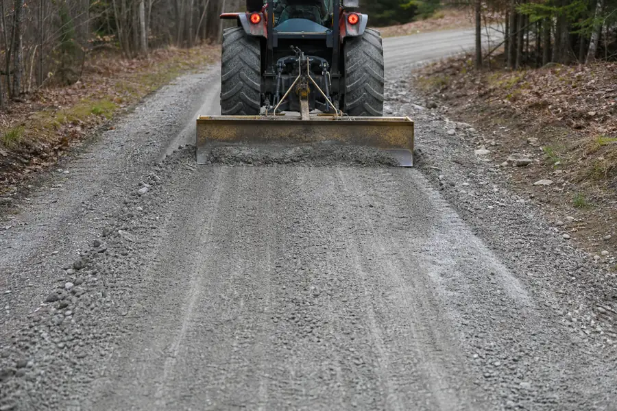 Tractor with a box blade regrading a washboarded gravel driveway