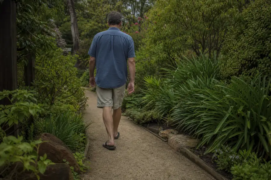 Homeowner walking along a compacted squeegee garden path bordered by plants