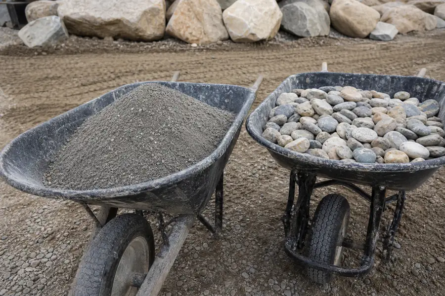 Wheelbarrow of crusher fines beside a wheelbarrow of river rock on a job site